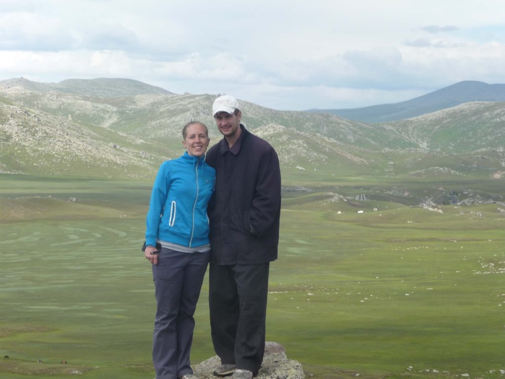 Couple posing on the edge of a cliff overlooking the valley in the mountains of Xinjiang