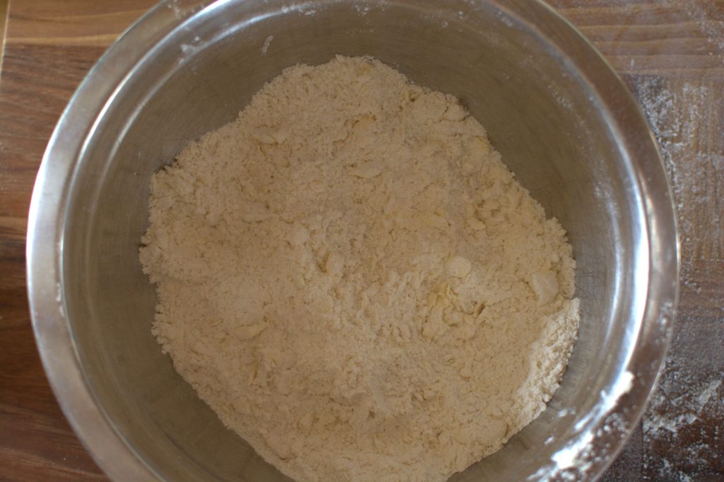 A bowl with flour mixture with butter cubes worked in 