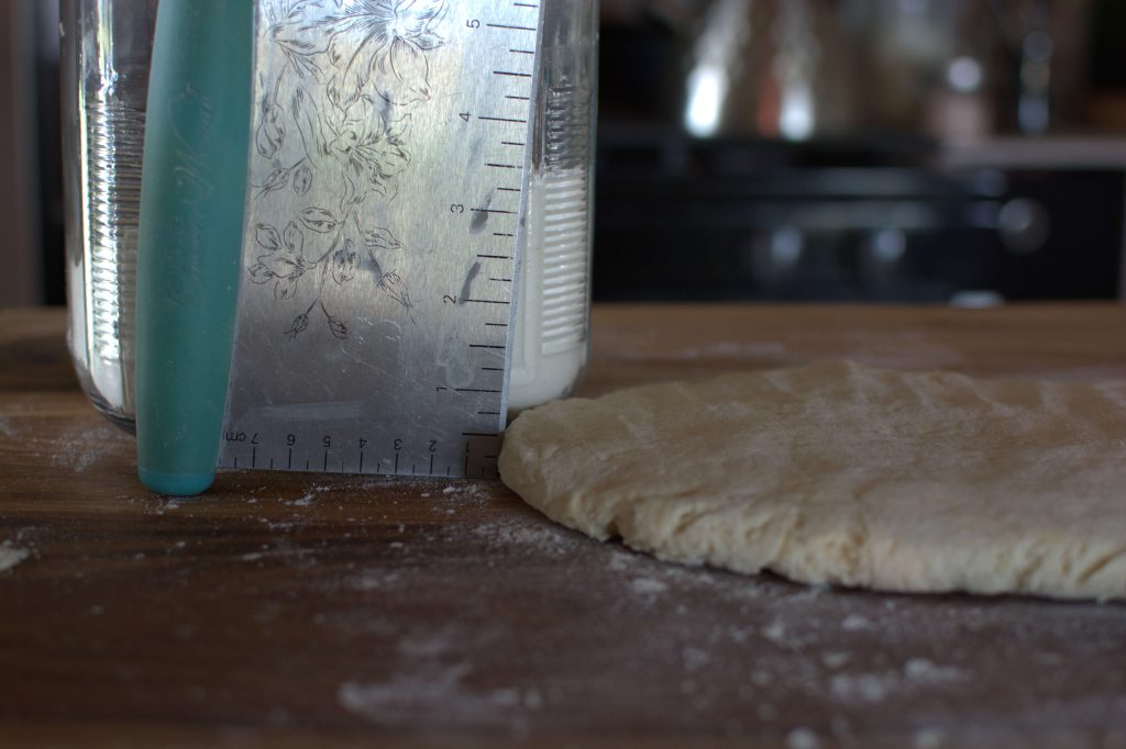 biscuit dough flattened out with dough scraper showing half inch thickness