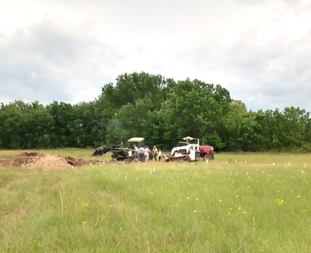 Tractors and a skid steer stuck in mud and men working to free them